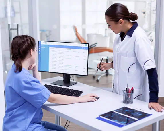 Two medical professionals looking at a computer screen.